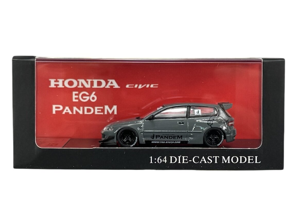 Model samochodu w skali 1:64 w kolorze szarym, umieszczony w pudełku z napisem \'HONDA CIVIC EG6 PANDEM\'. Na pudełku widnieje również napis \'1:64 DIE-CAST MODEL\'.