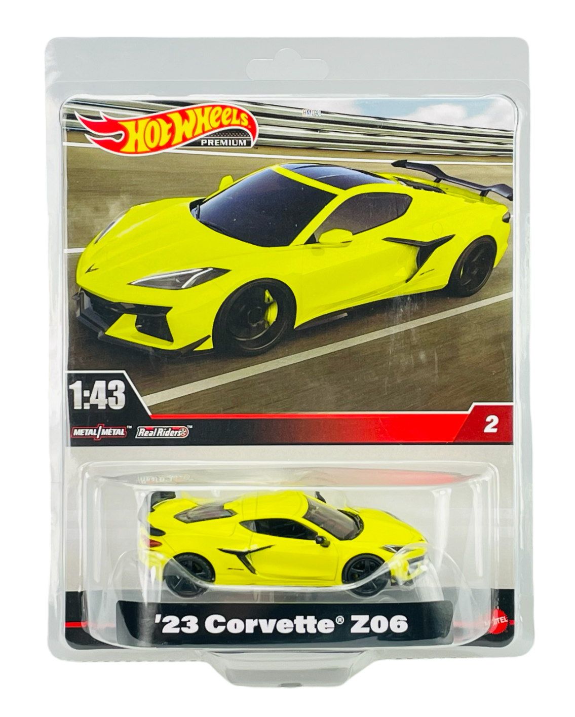 Opakowanie z modelem samochodu w skali 1:43, przedstawiające żółty samochód sportowy z napisem \'23 Corvette Z06\'. Widoczne logo \'Hot Wheels\' oraz tekst \'Metal/Metal\' i \'Real Riders\'.
