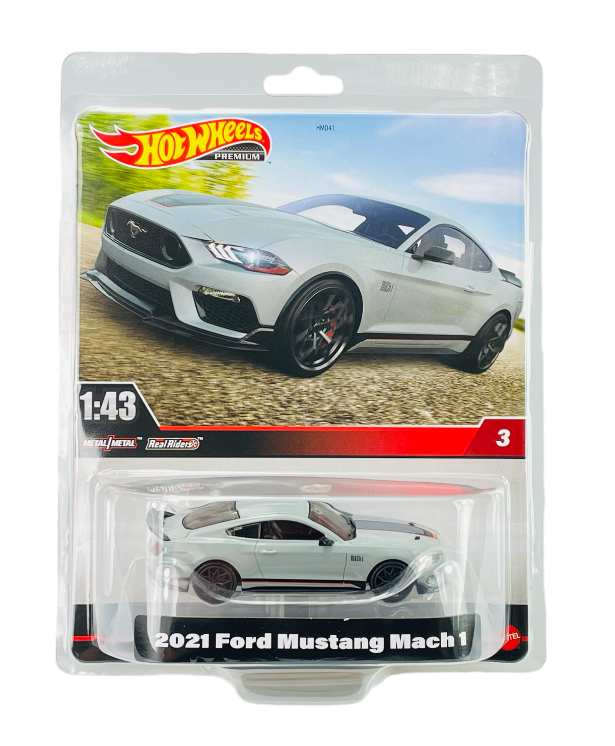 Opakowanie z modelem samochodu Hot Wheels Premium, przedstawiające biały 2021 Ford Mustang Mach 1 w skali 1:43. Na opakowaniu widnieje logo Hot Wheels oraz napis \'2021 Ford Mustang Mach 1\'.
