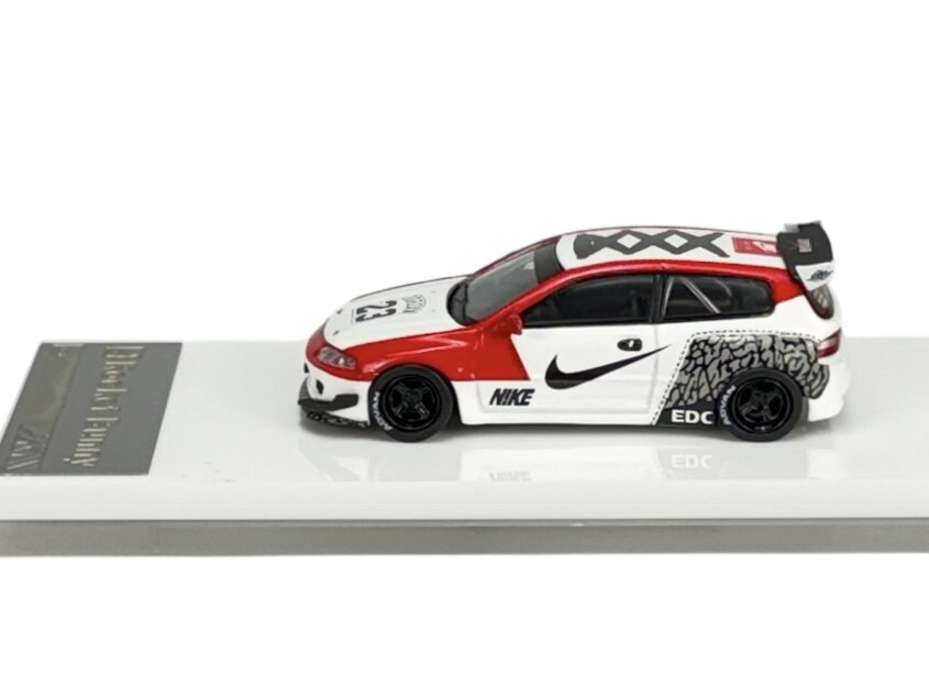 Model samochodu w skali 1:64 w kolorach czerwonym, białym i czarnym z logo Nike oraz wzorem przypominającym opony. Na masce widoczny numer 23, a na podstawce napis \'Rocket Bunny\'.