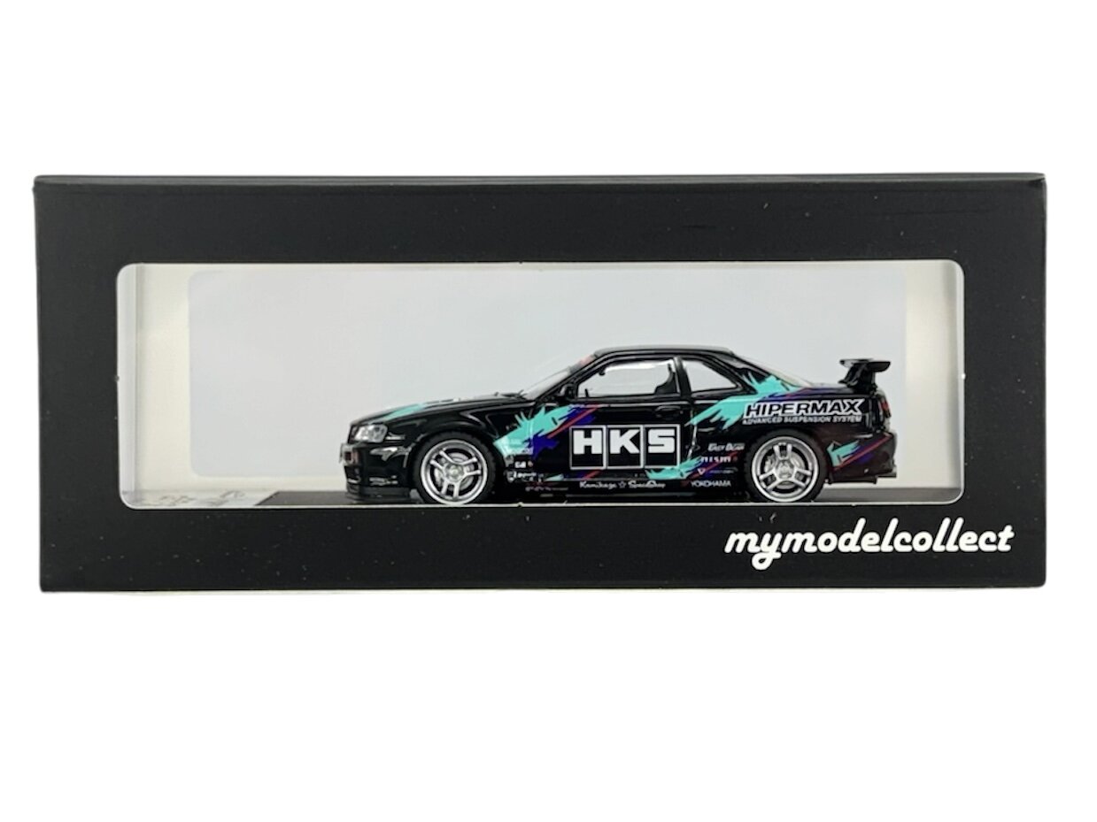 Model samochodu w skali 1:64 w czarnej gablocie z przezroczystym frontem. Na samochodzie widoczne są napisy \'HKS\' i \'HIPERMAX\', a na gablocie napis \'mymodelcollect\'.