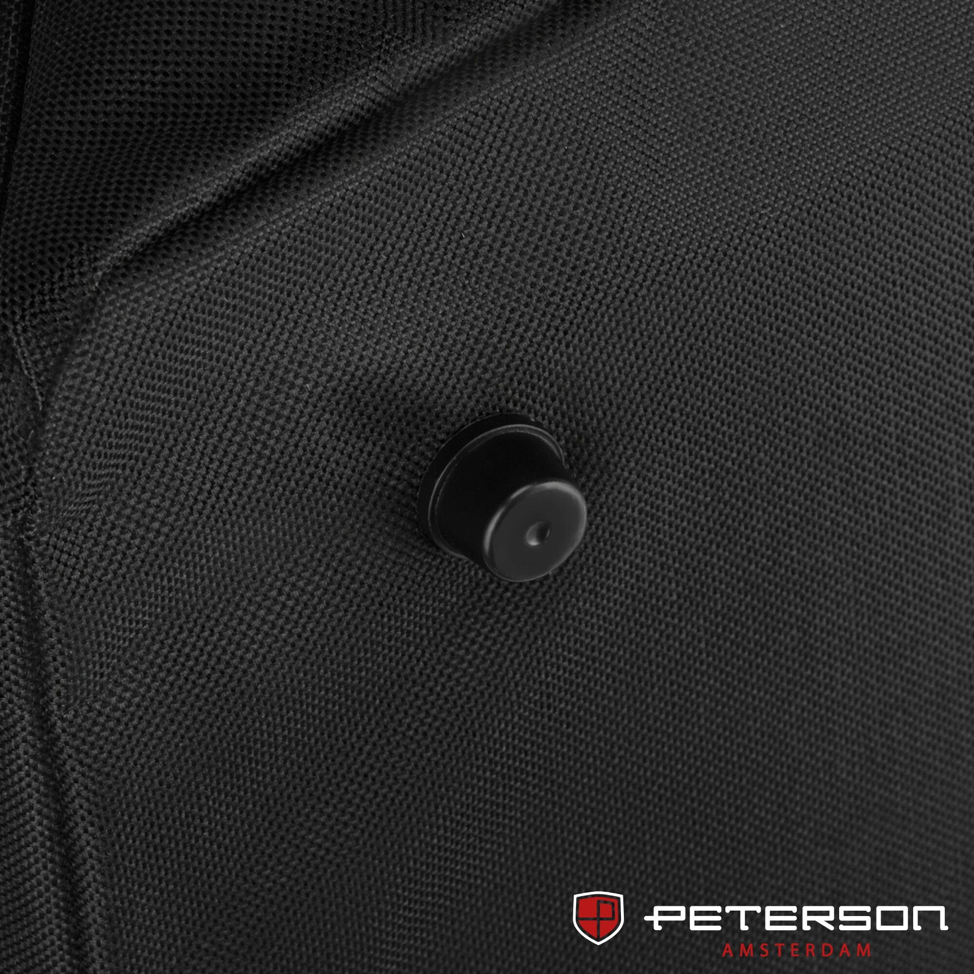 Czarna torba podróżna sportowa z widocznym czarnym guzikiem na teksturowanej powierzchni. W prawym dolnym rogu znajduje się logo \'Peterson Amsterdam\'.