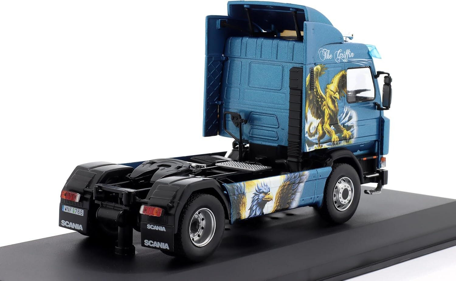 Model ciężarówki w kolorze niebieskim z grafiką gryfa na kabinie. Na tylnej części pojazdu widoczne jest logo \'Scania\'.