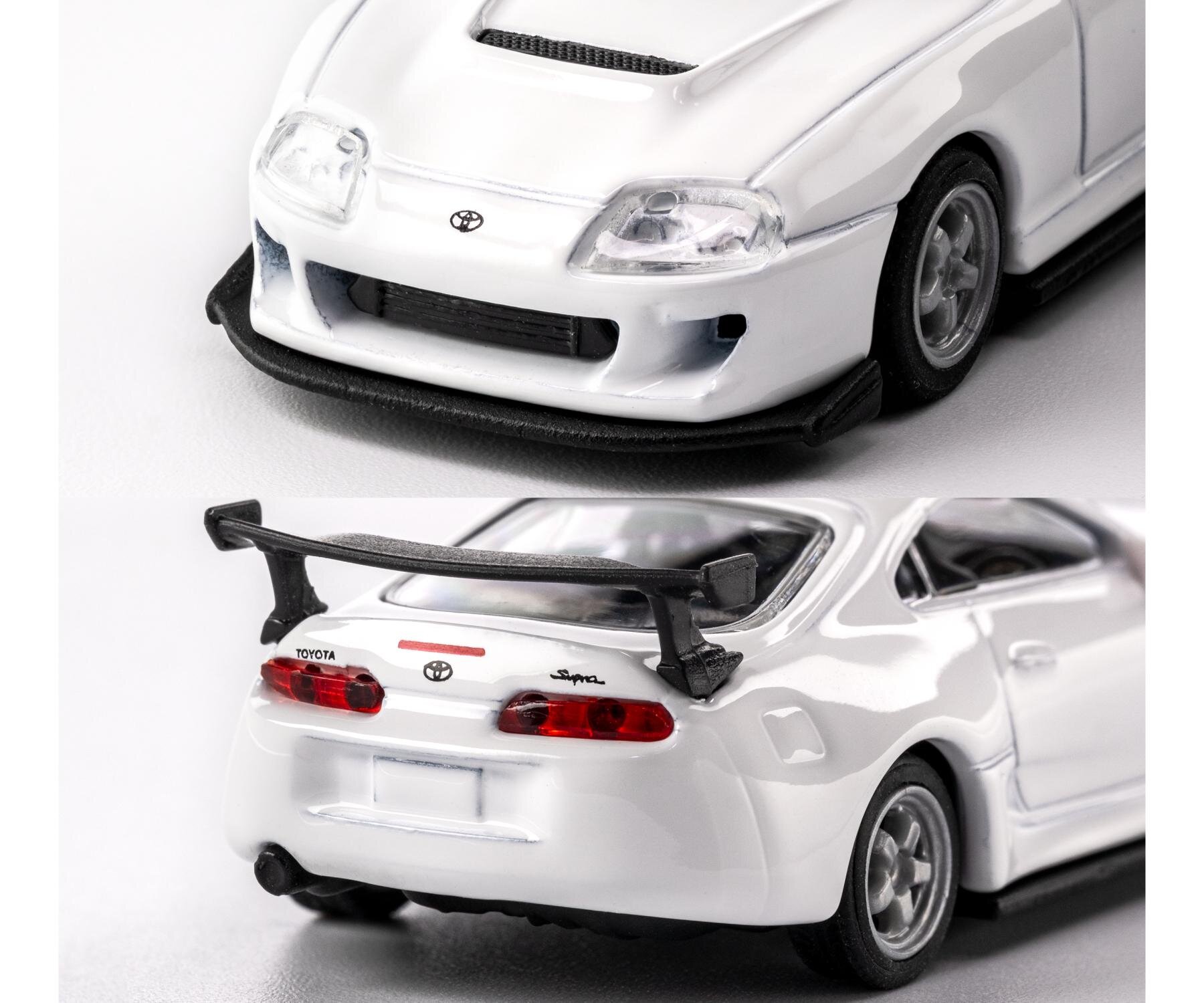 Model samochodu w skali 1:64 przedstawiający białą Toyotę Suprę z widocznym logo Toyota na przodzie i napisem \'Supra\' z tyłu. Samochód ma szczegółowe elementy, takie jak reflektory, zderzaki i spojler.