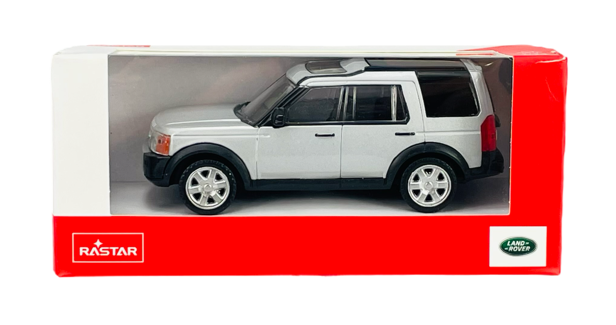 Srebrny model samochodu w skali 1:43 w opakowaniu z logo RASTAR i Land Rover. Opakowanie jest czerwono-białe z przezroczystym frontem.