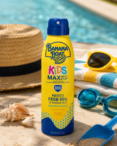 Na obrazie znajduje się żółta butelka sprayu do opalania Banana Boat Kids Max Protect & Play SPF 100, stojąca na tle plażowych akcesoriów, takich jak kapelusz, ręcznik, okulary przeciwsłoneczne i muszle. Tekst na butelce: \'Banana Boat Kids Max Protect & Play 100 Protects from 99% of burning rays Pediatrician tested\'.