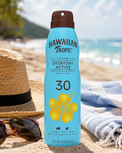 Na plaży znajduje się niebieska butelka sprayu przeciwsłonecznego HAWAIIAN TROPIC z filtrem SPF 30, ozdobiona żółtym kwiatem hibiskusa. W tle widać piasek, kapelusz, okulary przeciwsłoneczne i ręcznik.