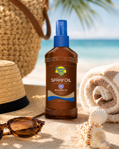 Na plaży znajduje się brązowa butelka z niebieskim dozownikiem, na której widnieje napis \'Banana Boat Spray Oil SPF 15\'. W tle widać kapelusz, ręcznik, muszle i okulary przeciwsłoneczne.
