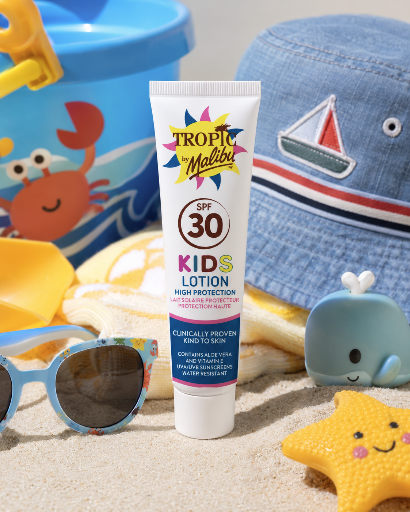 Na obrazie znajduje się tubka balsamu do opalania dla dzieci z napisem \'Tropic by Malibu SPF 30 Kids Lotion High Protection\'. W tle widoczne są dziecięce akcesoria plażowe, takie jak wiaderko, okulary przeciwsłoneczne i kapelusz.