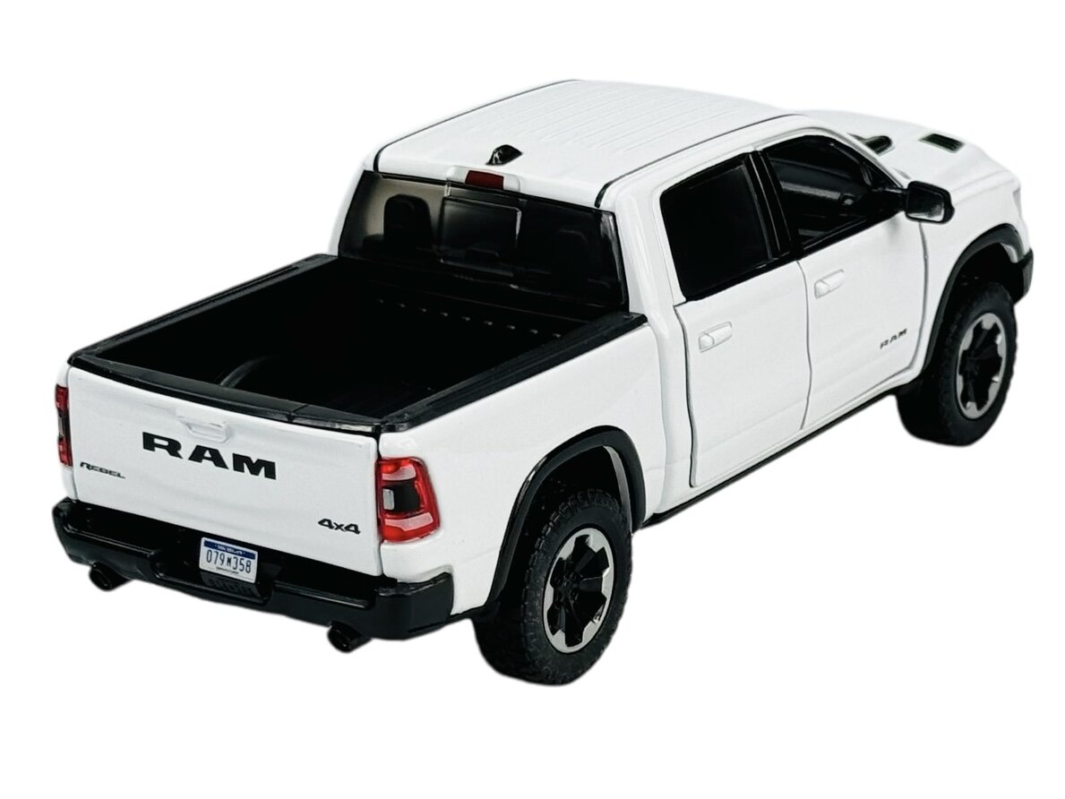 Biały model samochodu typu pickup z czarnymi elementami, oznaczony napisem \'RAM\' na tylnej klapie. Na tablicy rejestracyjnej widoczny jest numer \'079M358\'.