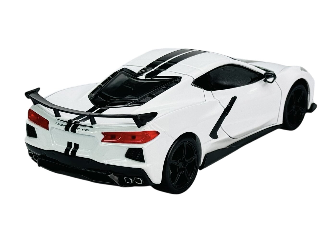 Biały model samochodu sportowego z czarnymi pasami na karoserii i czarnymi felgami. Na tylnej części pojazdu widoczny jest napis \'Corvette\'.