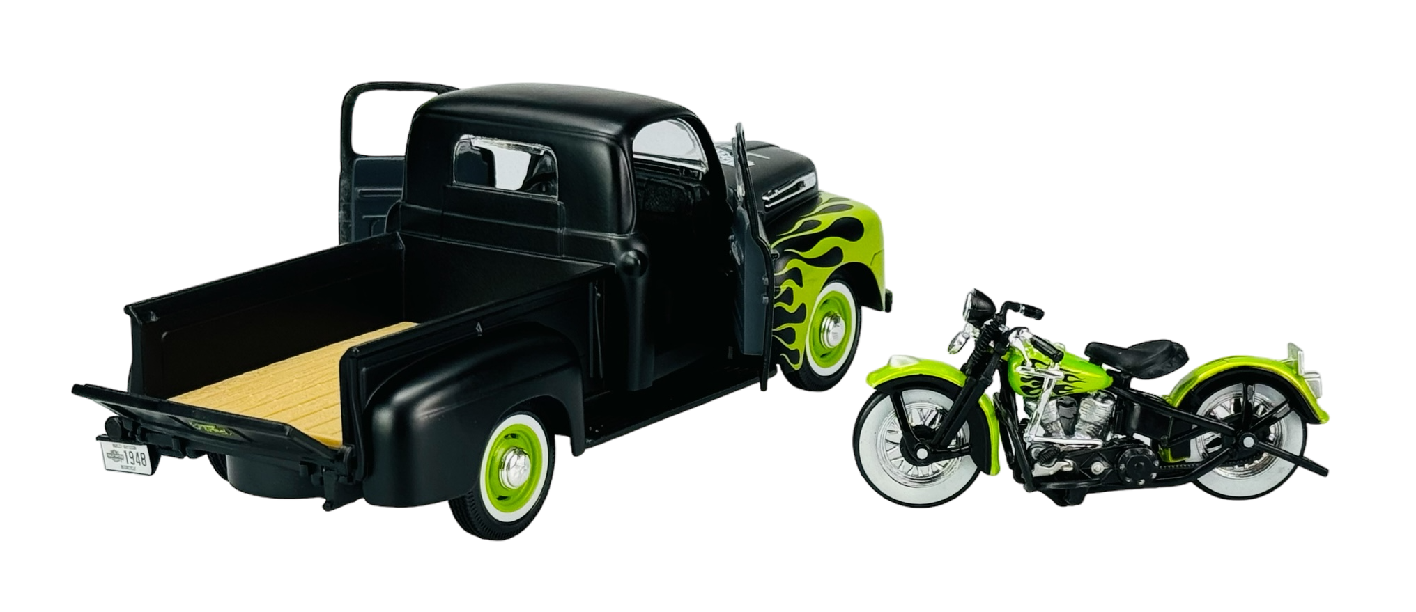 Model czarnego pickupa z otwartymi drzwiami i zielonymi płomieniami na bokach stoi obok zielono-czarnego motocykla. Oba pojazdy mają białe opony.
