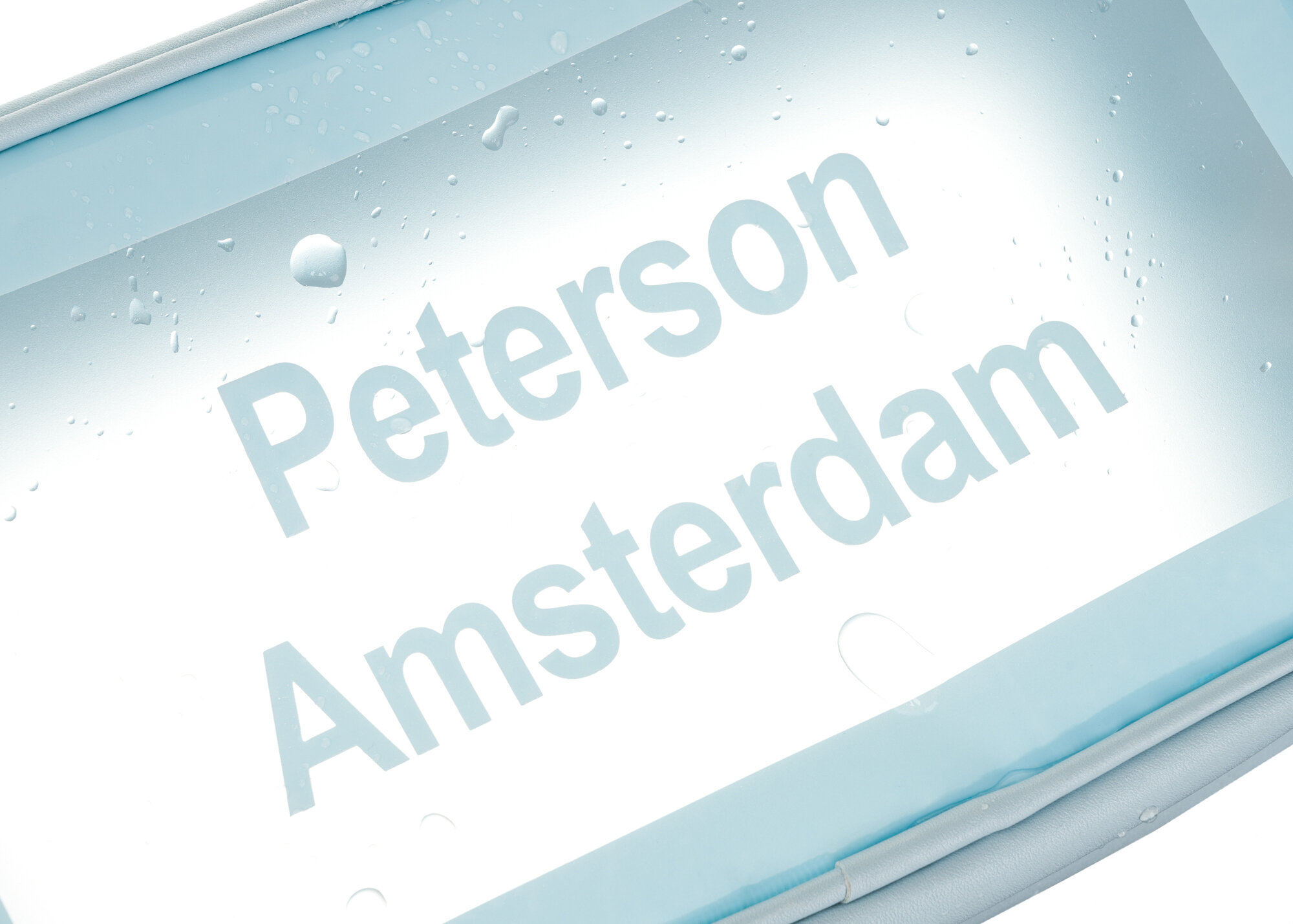 Obraz przedstawia przezroczystą powierzchnię z niebieską ramką, na której widnieje tekst \'Peterson Amsterdam\'. Na powierzchni znajdują się krople wody.