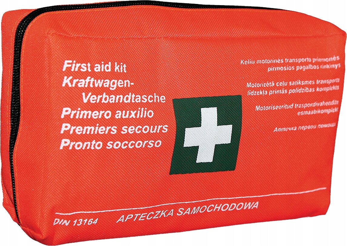 Czerwona apteczka pierwszej pomocy z białym krzyżem na zielonym tle. Na apteczce widoczny jest tekst: \'First aid kit, Kraftwagen-Verbandtasche, Primero auxilio, Premiers secours, Pronto soccorso\' oraz \'DIN 13164 APTECZKA SAMOCHODOWA\'.