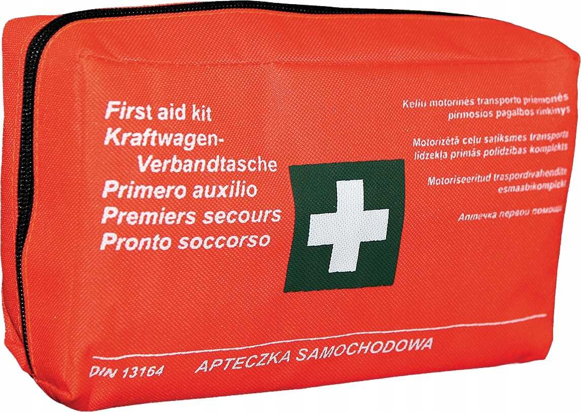 Czerwona apteczka pierwszej pomocy z białym krzyżem na zielonym tle. Na apteczce widoczny jest tekst: \'First aid kit, Kraftwagen-Verbandtasche, Primero auxilio, Premiers secours, Pronto soccorso\' oraz \'DIN 13164 APTECZKA SAMOCHODOWA\'.