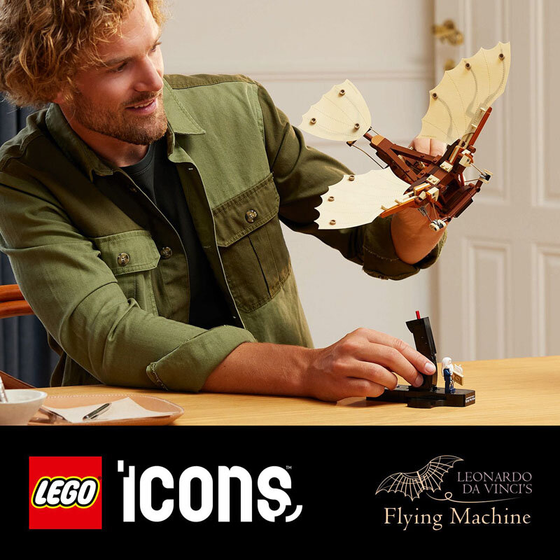 Osoba trzyma model maszyny latającej z klocków LEGO o jasnych skrzydłach i brązowej konstrukcji. Na dole obrazu widoczne jest logo LEGO i napis \'Icons\', a także \'Leonardo da Vinci\'s Flying Machine\'.