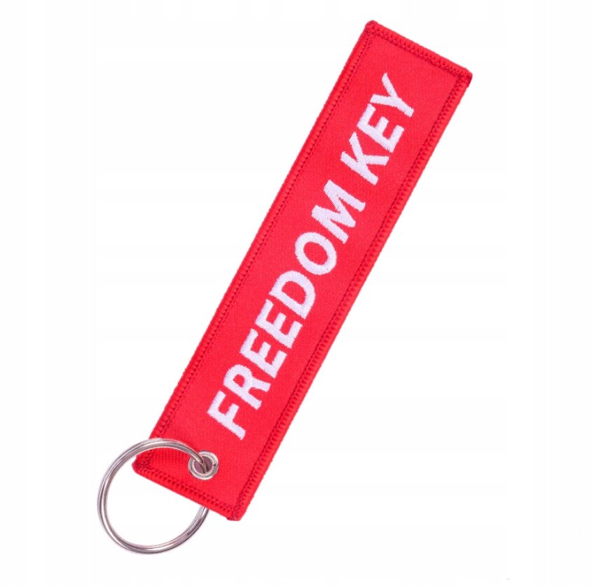 Czerwony brelok z napisem \'FREEDOM KEY\' i metalowym kółkiem do zawieszania kluczy.