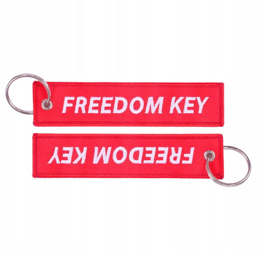 Dwa czerwone breloki z napisem \'FREEDOM KEY\' w białym kolorze, każdy z metalowym kółkiem do zawieszania.