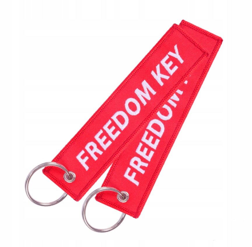 Dwa czerwone breloki z napisem \'FREEDOM KEY\' w białym kolorze, każdy z metalowym kółkiem do zawieszania kluczy.