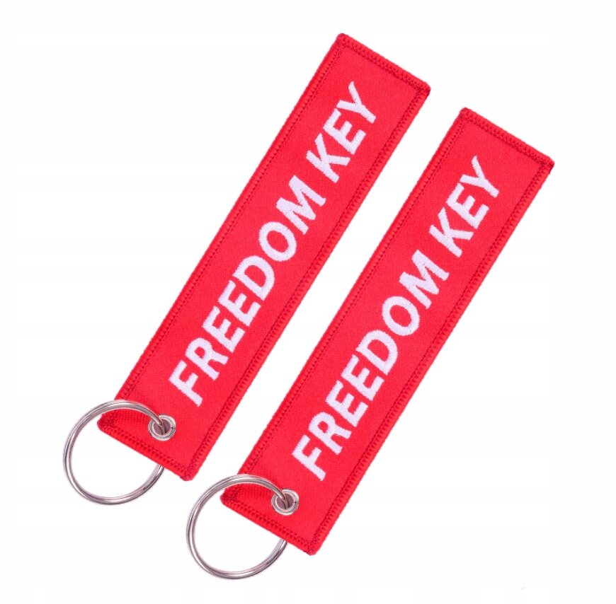 Dwa czerwone breloki z napisem \'FREEDOM KEY\' w białym kolorze, każdy z metalowym kółkiem do zawieszania kluczy.