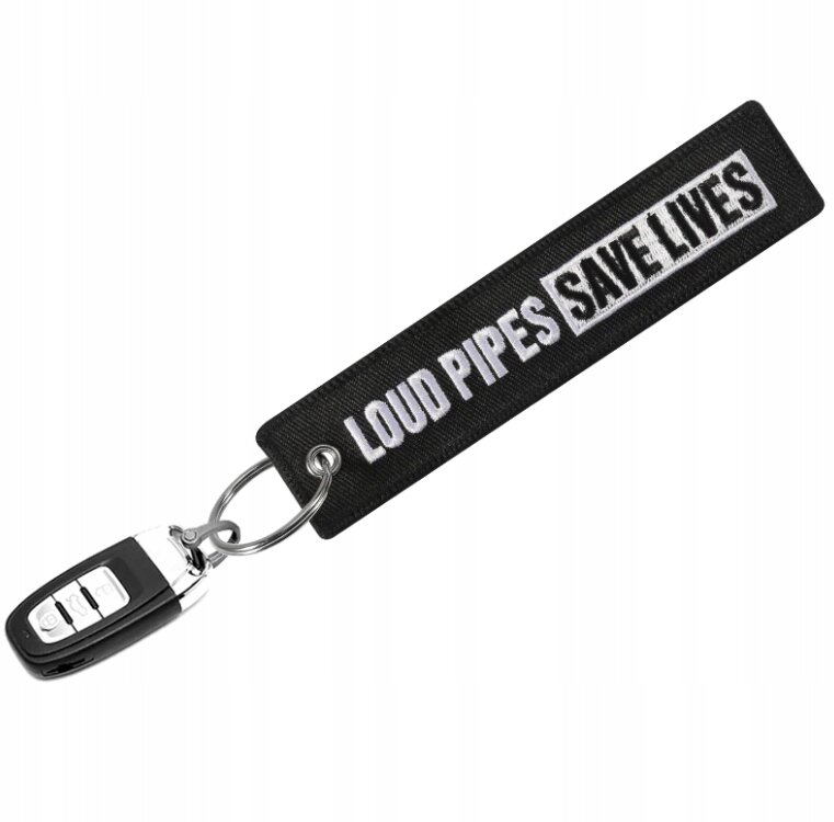 Czarny brelok do kluczy z napisem \'LOUD PIPES SAVE LIVES\' w białym kolorze, przymocowany do metalowego kółka z kluczykiem samochodowym.
