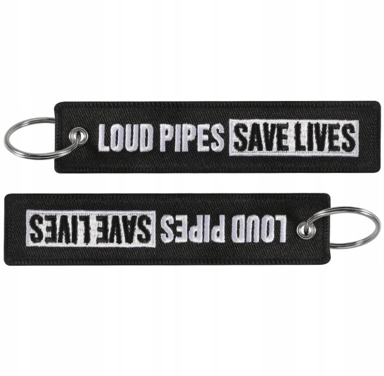Czarny brelok do kluczy z napisem \'LOUD PIPES SAVE LIVES\' w białym kolorze, widoczny z obu stron. Brelok posiada metalowe kółko do zawieszenia kluczy.