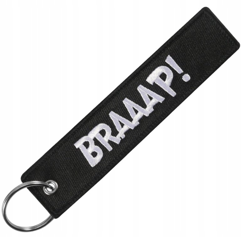 Czarny brelok z białym napisem \'BRAAAP!\' i metalowym kółkiem do kluczy.