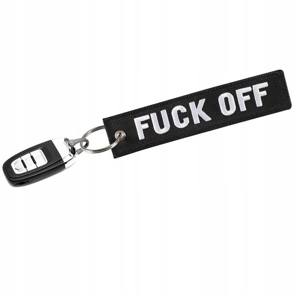Czarny brelok do kluczy z białym napisem \'FUCK OFF\', przymocowany do metalowego kółka z kluczykiem samochodowym.