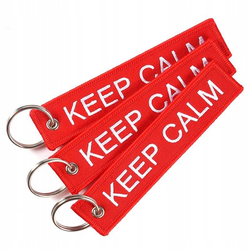 Trzy czerwone breloki z napisem \'KEEP CALM\' w białym kolorze, każdy z metalowym kółkiem do zawieszania.