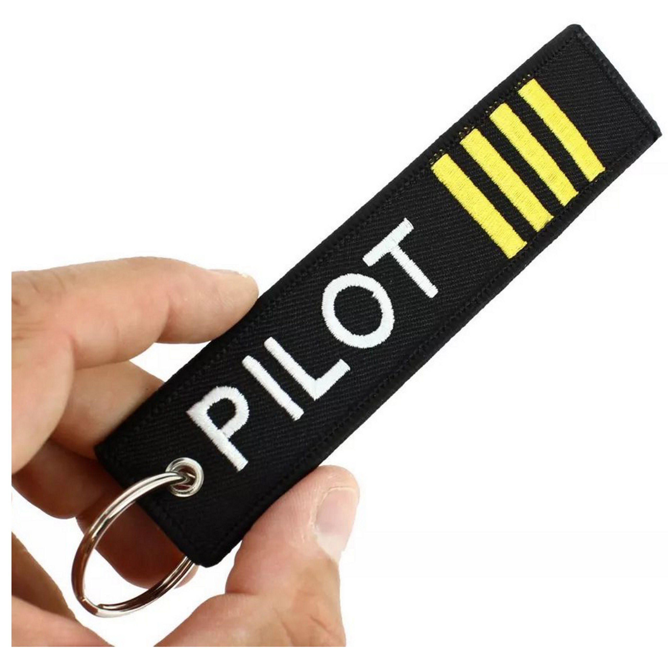 Czarny brelok do kluczy z napisem \'PILOT\' w kolorze białym oraz trzema żółtymi paskami. Brelok jest trzymany w dłoni i posiada metalowe kółko do zawieszenia.