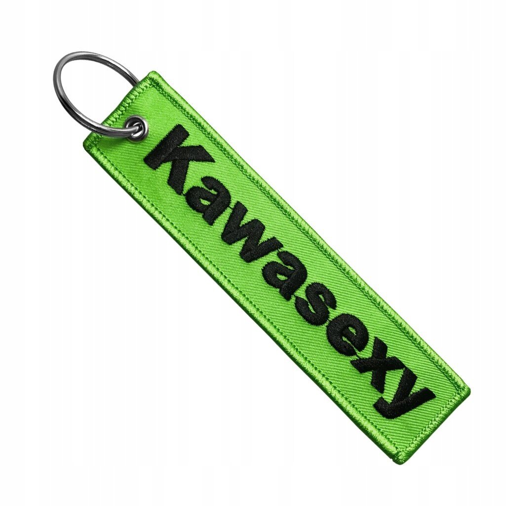 Zielony brelok z napisem \'Kawasexy\' w czarnym kolorze, posiada metalowe kółko do zawieszenia.