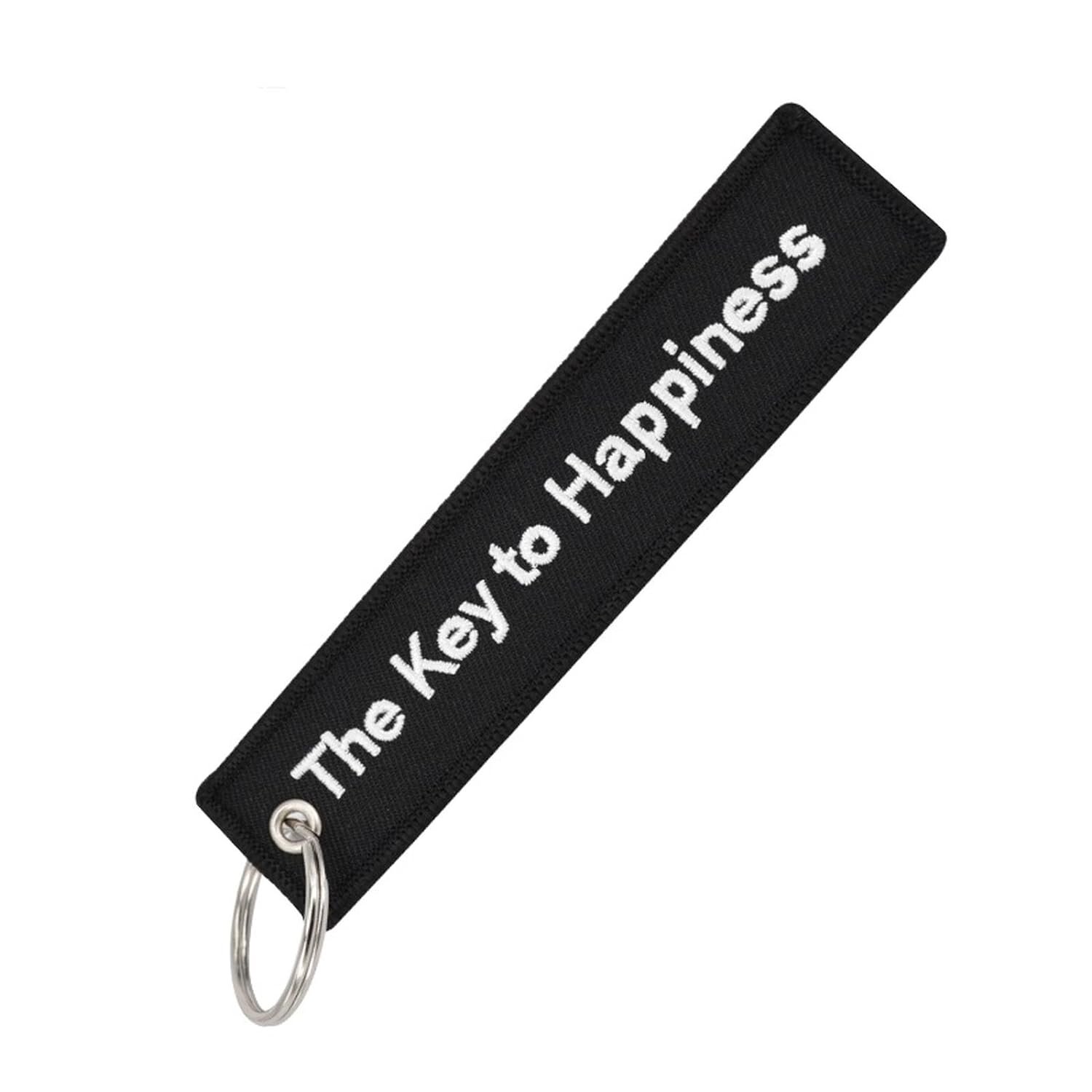 Czarny brelok do kluczy z białym napisem \'The Key to Happiness\'.