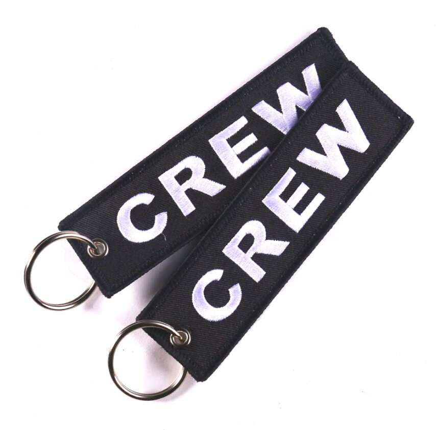 Dwa czarne breloki z białym napisem \'CREW\', każdy z metalowym kółkiem do kluczy.