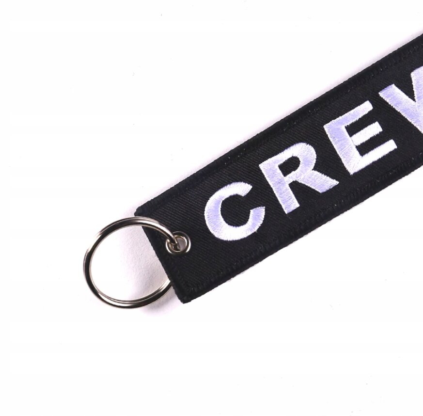 Czarny brelok z białym napisem \'CREW\' i metalowym kółkiem do kluczy.