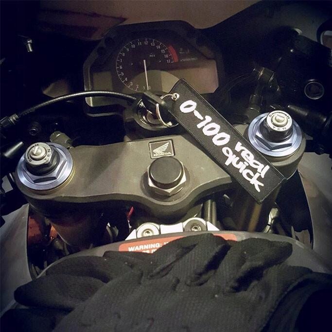 Na zdjęciu widoczny jest kokpit motocykla z brelokiem z napisem \'0-100 real quick\'. Na kierownicy znajduje się logo producenta motocykla.