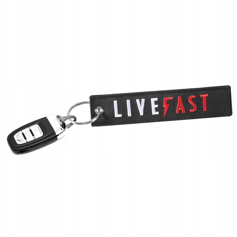 Czarny brelok z napisem \'LIVE FAST\' w kolorach białym i czerwonym, przymocowany do kluczyka samochodowego.