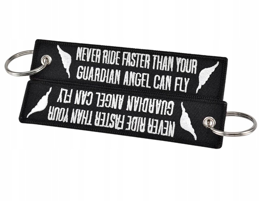 Czarne breloki z białym napisem \'NEVER RIDE FASTER THAN YOUR GUARDIAN ANGEL CAN FLY\' oraz białym symbolem skrzydła po obu stronach. Każdy brelok ma metalowe kółko do zawieszenia kluczy.