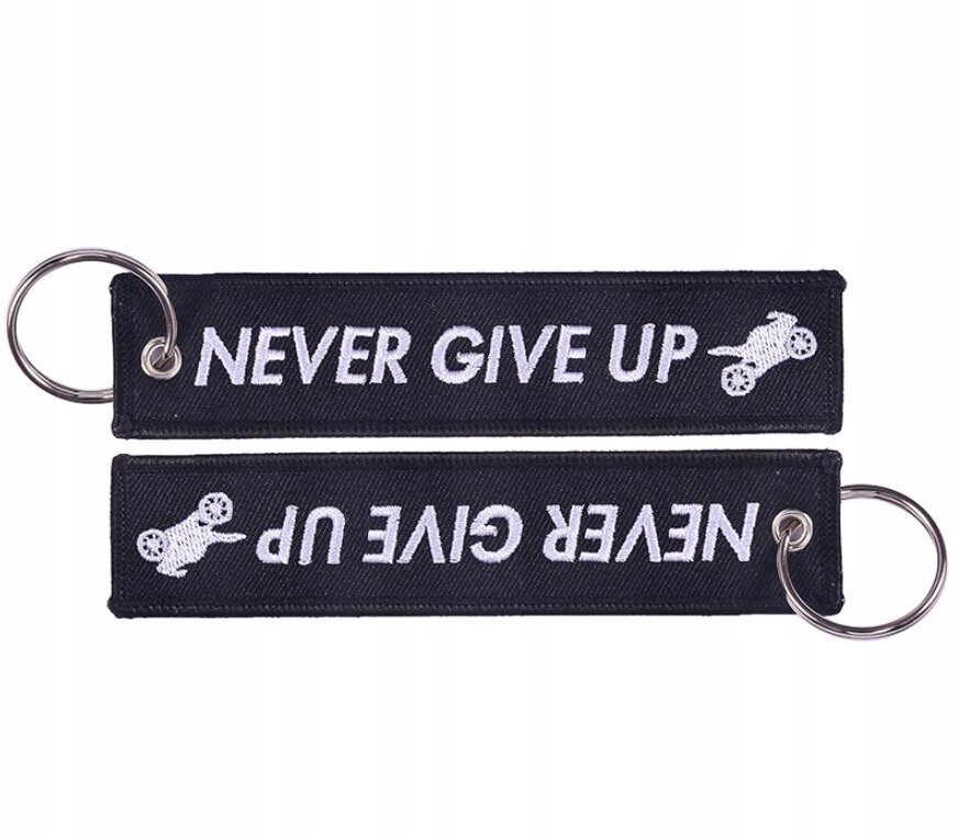 Czarny brelok z napisem \'NEVER GIVE UP\' i grafiką motocykla, posiada metalowe kółko do zawieszenia kluczy.