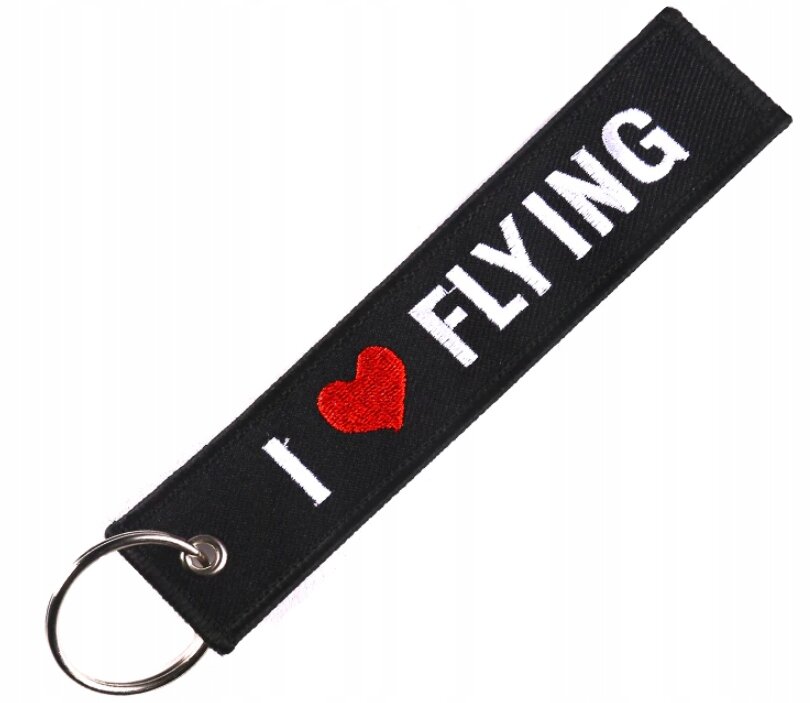 Czarny brelok z napisem \'I ❤️ FLYING\' w kolorze białym i czerwonym sercem, z metalowym kółkiem do zawieszania kluczy.