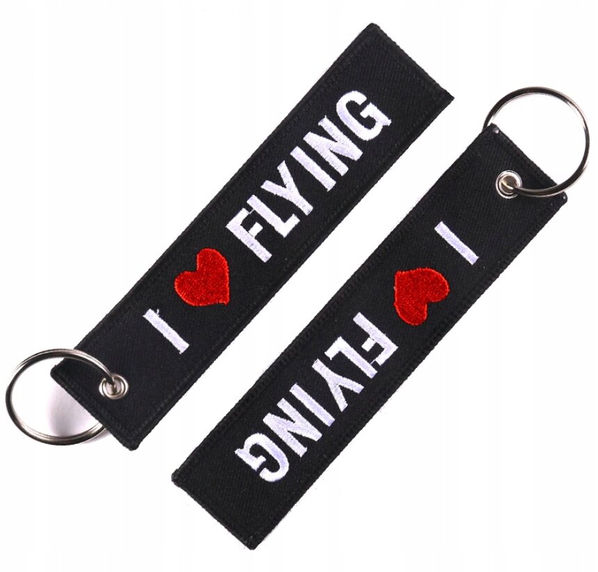 Dwa czarne breloki z napisem \'I ❤️ FLYING\' w białym kolorze i czerwonym sercem, każdy z metalowym kółkiem do zawieszenia.