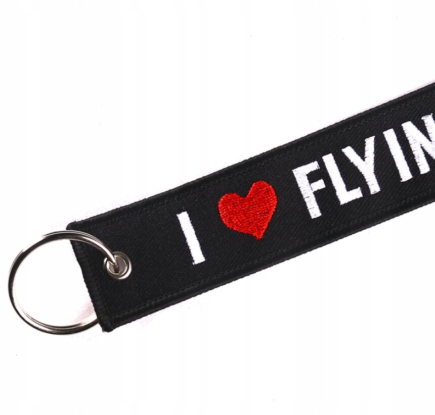 Czarny brelok z metalowym kółkiem, na którym widnieje napis \'I ❤️ FLYING\' w białym i czerwonym kolorze.