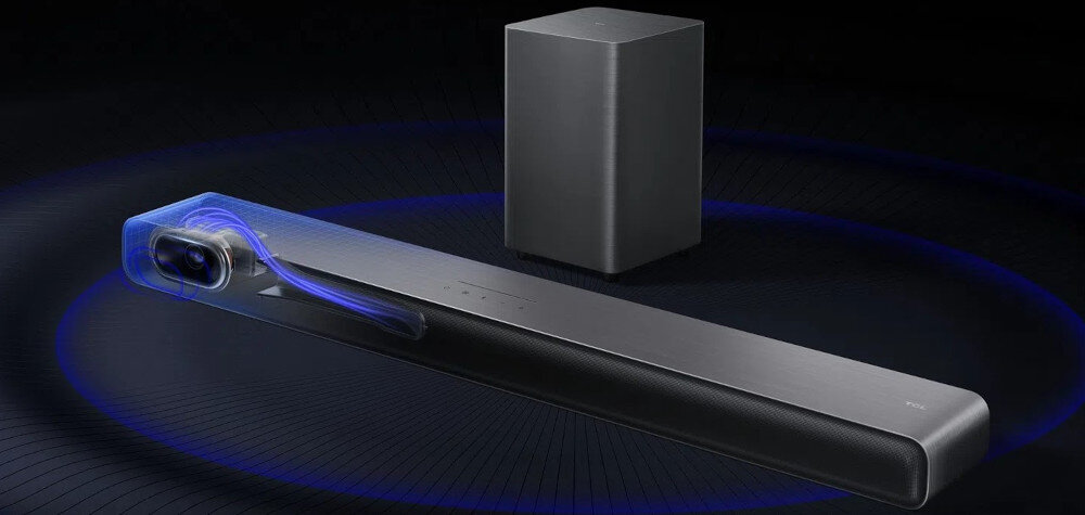 Na obrazie widoczny jest czarny soundbar oraz bezprzewodowy subwoofer na ciemnym tle. Soundbar ma smukły, nowoczesny design z delikatnym podświetleniem na jednym z końców.