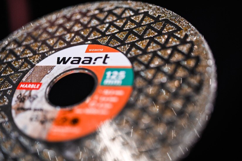 Na zdjęciu widoczna jest tarcza diamentowa z logo \'waart\' oraz oznaczeniem \'125 mm\'. Tarcza ma wzór w kształcie trójkątów i jest przeznaczona do cięcia materiałów takich jak gres, beton i glazura.