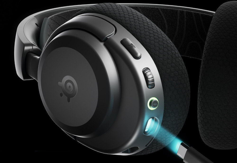 Czarne słuchawki nauszne z widocznymi przyciskami i portami na jednej z muszli. Na muszli znajduje się logo SteelSeries.
