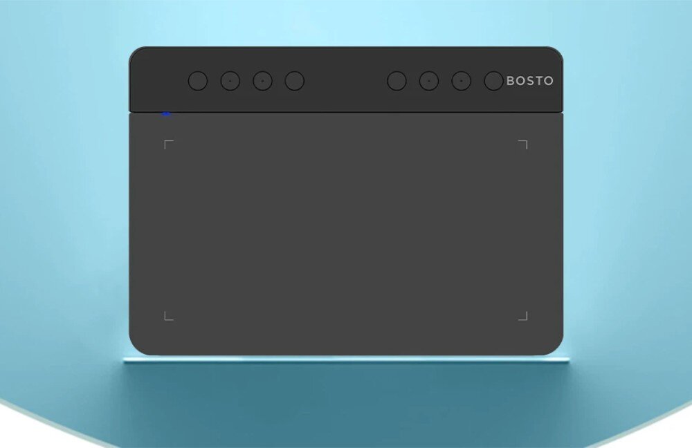 Na obrazie widoczny jest czarny tablet graficzny z sześcioma okrągłymi przyciskami na górze i napisem \'BOSTO\'.