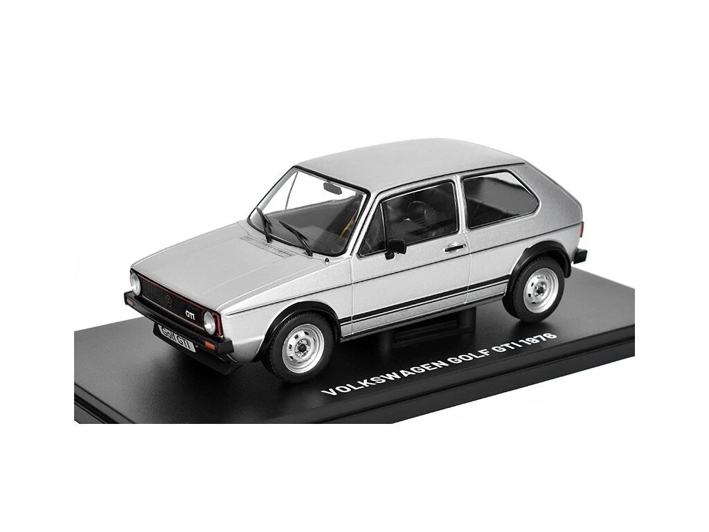 Srebrny model samochodu Volkswagen Golf GTI 1976 na czarnej podstawce z napisem \'VOLKSWAGEN GOLF GTI 1976\'.