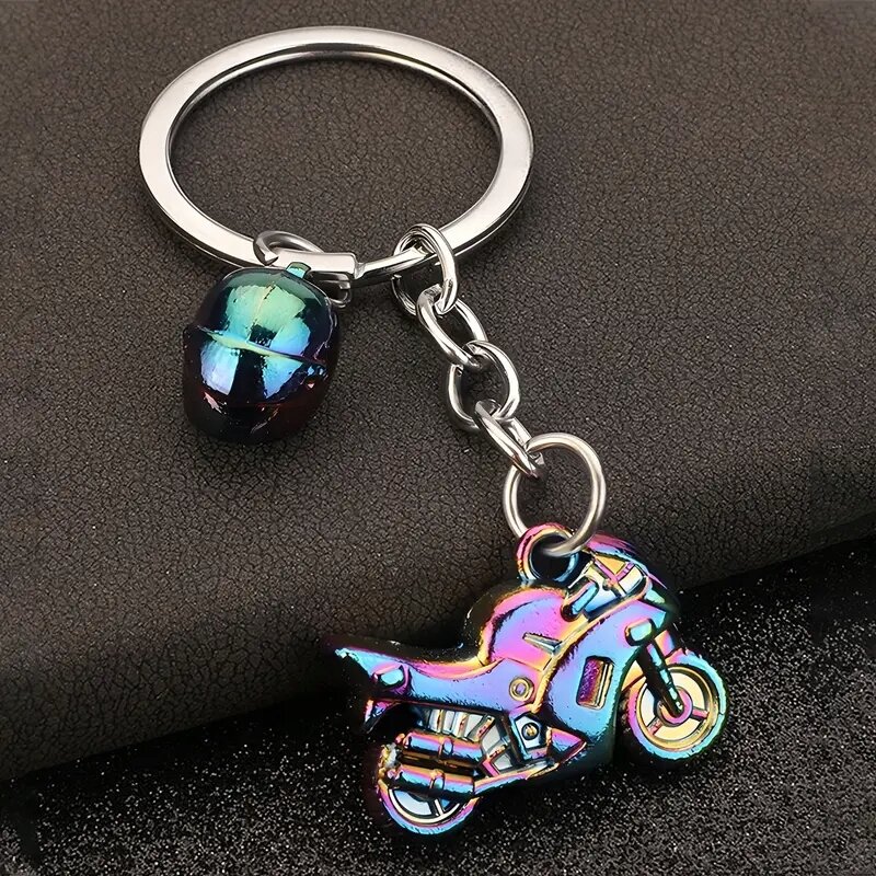 Brelok do kluczy z metalowym motywem motocykla i kasku w kolorze neochromu. Elementy są przymocowane do metalowego kółka na klucze.