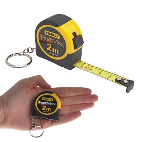 Na obrazie widoczna jest miara zwijana z napisem \'Stanley FatMax 2m\', która posiada brelok do kluczy. Miara jest prezentowana na dłoni oraz w pozycji rozwiniętej.