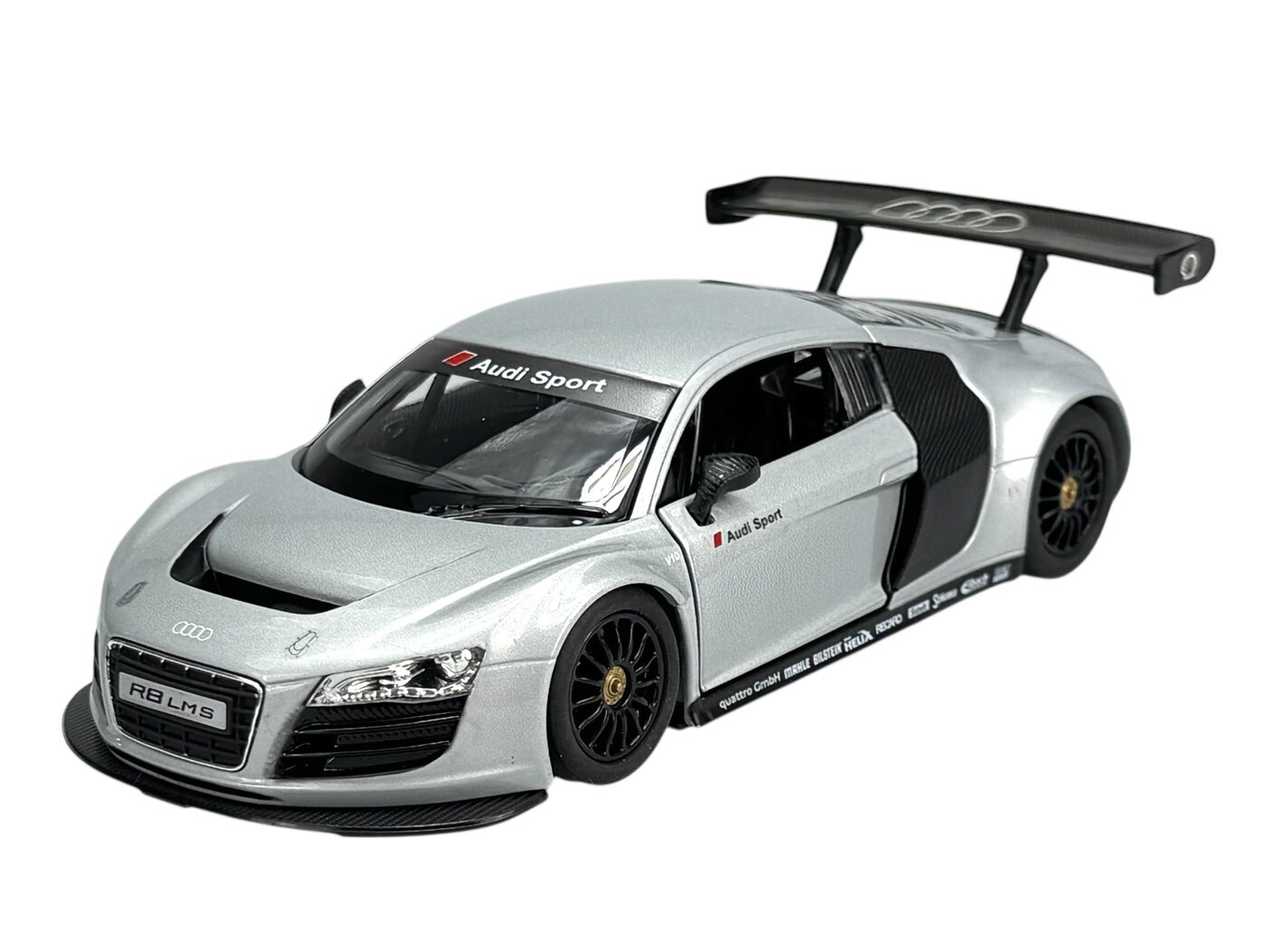 Srebrny model samochodu wyścigowego z napisem \'Audi Sport\' na przedniej szybie i dużym tylnym spojlerem. Na przodzie widoczne logo Audi oraz tablica z napisem \'R8 LMS\'.