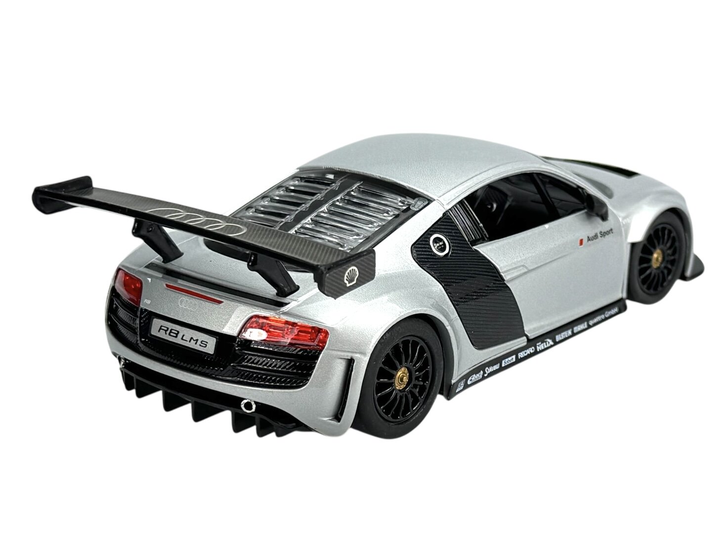 Srebrny model samochodu wyścigowego z dużym tylnym spojlerem i czarnymi detalami. Na tylnej tablicy rejestracyjnej widnieje napis \'R8 LMS\'.